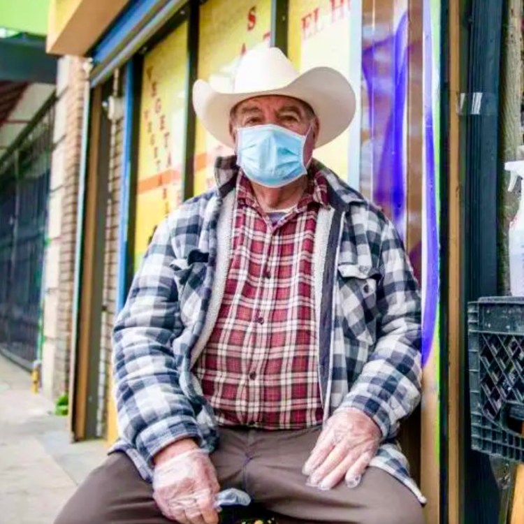 Older man wearing a cowboy hat, protective face mask and gloves